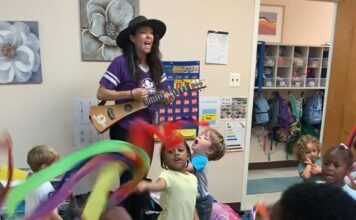 Children dancing while musician plays guitar and sing for them