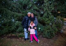 Family posing in front of Christmas trees