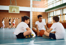 Growing a Social Circle Is Natural: Here’s How to Support Your Child as They Branch Out Group of elementary students talking while sitting on the floor during physical education class at school.