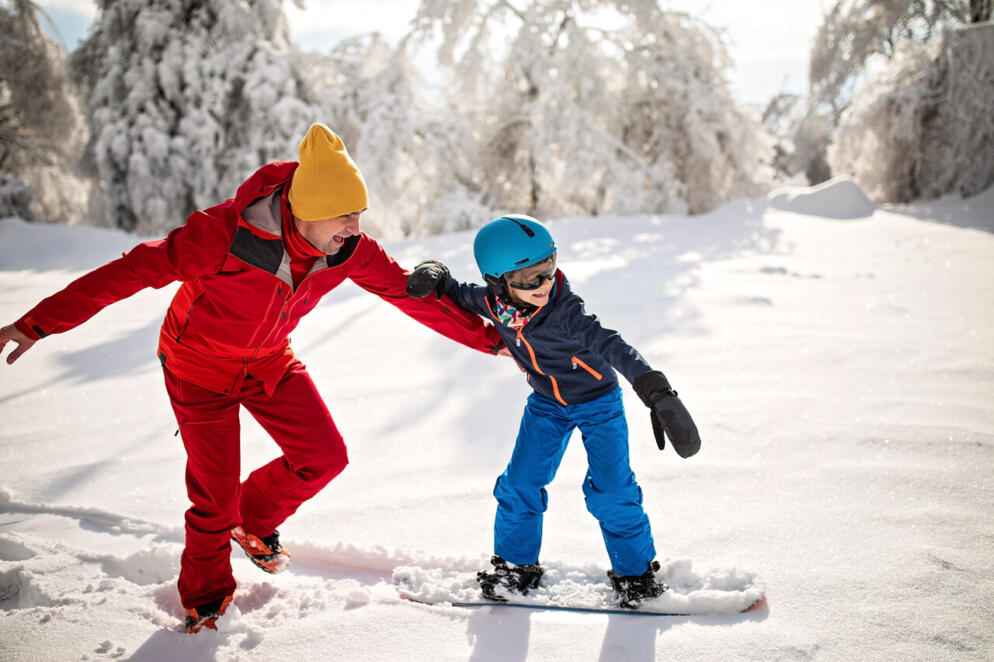 A father teaching his son to snowboard