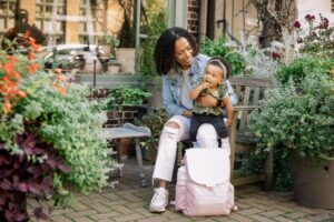 A mother with a baby and a pink Jool Baby relay diaper bag backpack