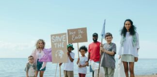 A group of kids on the beach holding signs that say "Save the Earth" and "Love the Earth"