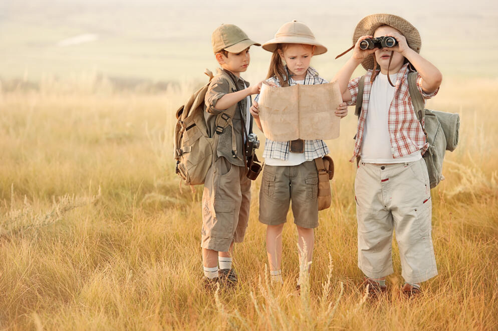 Group of kids travelers read a map at sunset