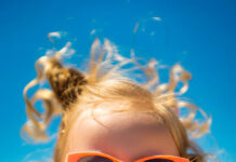 A little girl with sunglasses eating ice cream on the beach