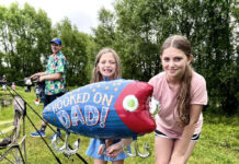 Summer Fun in the DMV This Weekend: June 20-21 Two girls, one holds up a large fish-shaped balloon that says "Hooked on Dad!"