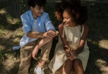 First Relationships for Teens: 5 Questions for Parents A teenage boy and girl sitting under a tree. The boy is giving the girl a flower.