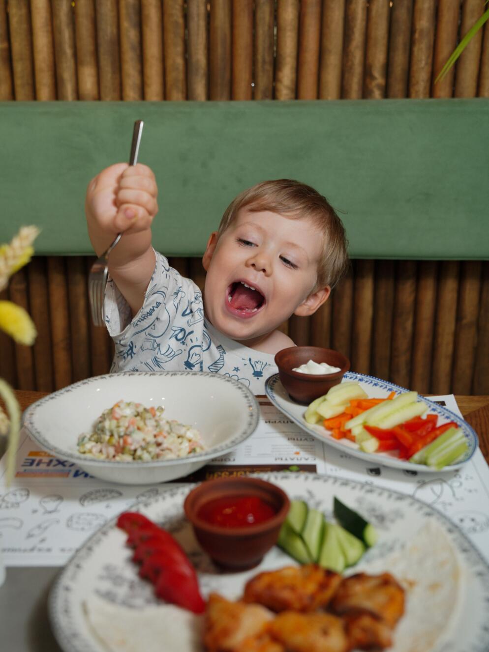 A young boy cheerfully enjoys healthy food at a restaurant.