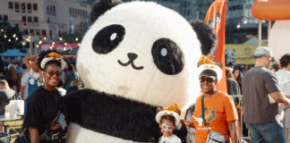 A family poses with a person in a large panda costume